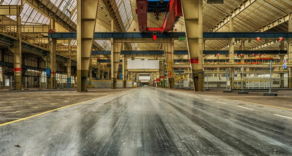 Pavilhão industrial com pavimento de betão liso e reflexo de luz